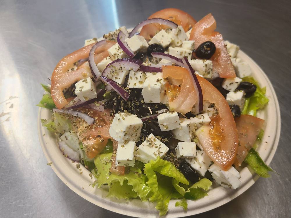 Greek salad with cubed feta, tomato wedges, red onion, black olives and lettuce.